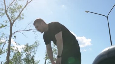 Bir erkek sporcu dışarıda spor alanında antrenman yapıyor. Beyaz erkek sporcu yaz parkında antrenman yapmadan önce ısınma egzersizi yapıyor.