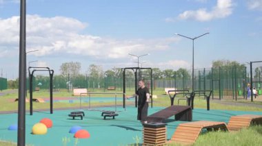 Bir erkek sporcu dışarıda spor alanında antrenman yapıyor. Beyaz erkek sporcu yaz parkında antrenman yapmadan önce ısınma egzersizi yapıyor.