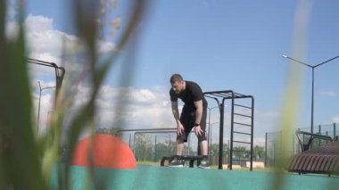 Bir erkek sporcu dışarıda spor alanında antrenman yapıyor. Beyaz erkek sporcu yaz parkında antrenman yapmadan önce ısınma egzersizi yapıyor.