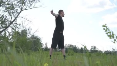 Bir erkek sporcu dışarıda spor alanında antrenman yapıyor. Beyaz erkek sporcu yaz parkında antrenman yapmadan önce ısınma egzersizi yapıyor.