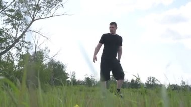 Bir erkek sporcu dışarıda spor alanında antrenman yapıyor. Beyaz erkek sporcu yaz parkında antrenman yapmadan önce ısınma egzersizi yapıyor.