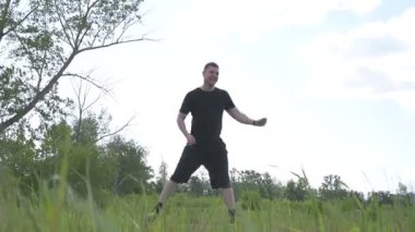 Bir erkek sporcu dışarıda spor alanında antrenman yapıyor. Beyaz erkek sporcu yaz parkında antrenman yapmadan önce ısınma egzersizi yapıyor.