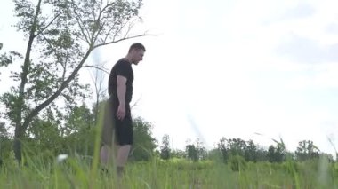 Bir erkek sporcu dışarıda spor alanında antrenman yapıyor. Beyaz erkek sporcu yaz parkında antrenman yapmadan önce ısınma egzersizi yapıyor.