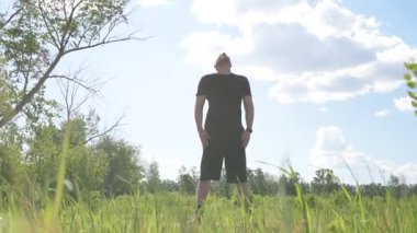 Bir erkek sporcu dışarıda spor alanında antrenman yapıyor. Beyaz erkek sporcu yaz parkında antrenman yapmadan önce ısınma egzersizi yapıyor.