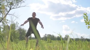 Bir erkek sporcu dışarıda spor alanında antrenman yapıyor. Beyaz erkek sporcu yaz parkında antrenman yapmadan önce ısınma egzersizi yapıyor.