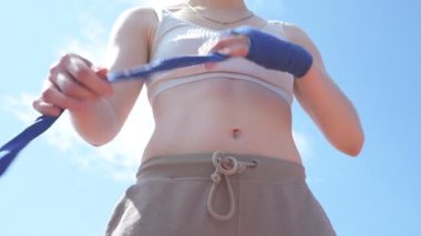 Profesyonel dövüşçü kız Muay Thai çalışmak için avuçlarını bantlıyor.