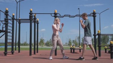 Sporcu erkek ve kız dışarıda boks antrenmanı yapıyorlar.