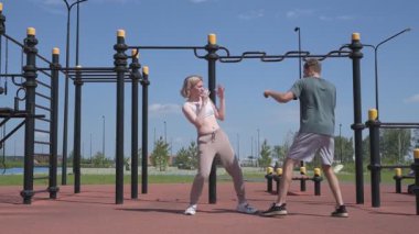 Sporcu erkek ve kız dışarıda boks antrenmanı yapıyorlar.