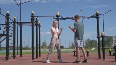 Sporcu erkek ve kız dışarıda boks antrenmanı yapıyorlar.