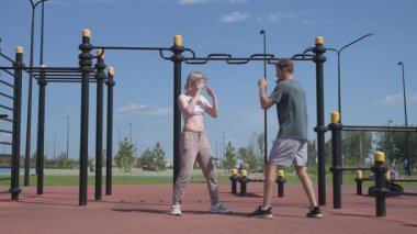 Sporcu erkek ve kız dışarıda boks antrenmanı yapıyorlar.