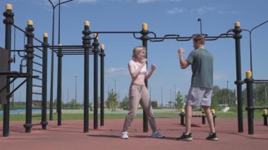 Sporcu erkek ve kız dışarıda boks antrenmanı yapıyorlar.