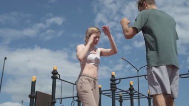 Sporcu erkek ve kız dışarıda boks antrenmanı yapıyorlar.