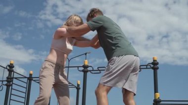 Sporcu erkek ve kız dışarıda boks antrenmanı yapıyorlar.