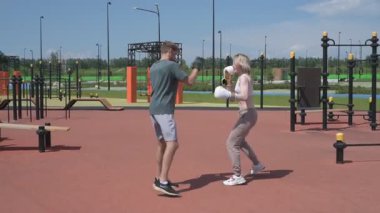 Sporcu erkek ve kız dışarıda boks antrenmanı yapıyorlar.