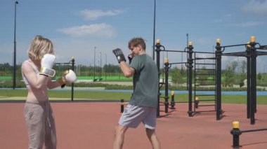 Sporcu erkek ve kız dışarıda boks antrenmanı yapıyorlar.