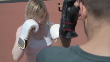 Sporcu erkek ve kız dışarıda boks antrenmanı yapıyorlar.