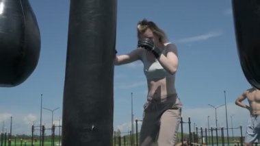 Sporcu erkek ve kız dışarıda boks antrenmanı yapıyorlar.