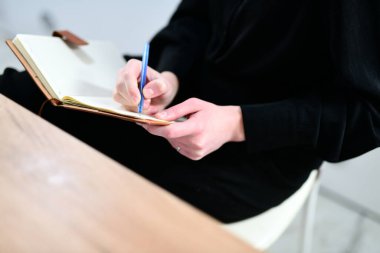 Akıllı kız öğrenci masasında otururken bir günlüğe yazar.