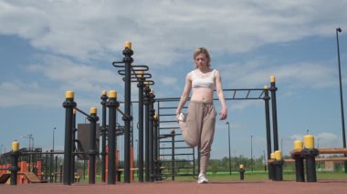 Genç beyaz kadın sporcu spor sahasında antrenman yapıyor.