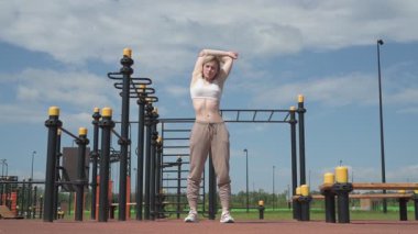 Genç beyaz kadın sporcu spor sahasında antrenman yapıyor.