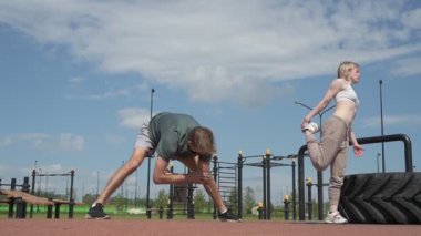 Beyaz erkek ve kadın sporcular spor sahasında antrenman yapıyor.