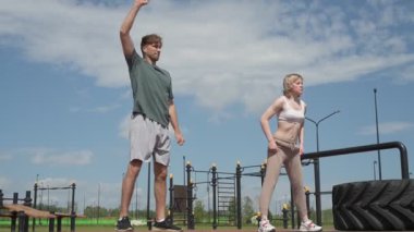 Beyaz erkek ve kadın sporcular spor sahasında antrenman yapıyor.