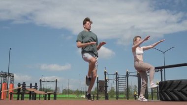 Beyaz erkek ve kadın sporcular spor sahasında antrenman yapıyor.