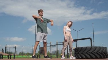 Beyaz erkek ve kadın sporcular spor sahasında antrenman yapıyor.