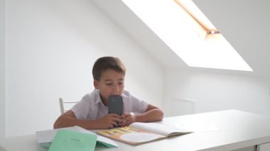 Küçük okul çocuğu ödev yapıyor, kalemle deftere yazıyor.