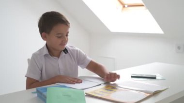 Küçük okul çocuğu ödev yapıyor, kalemle deftere yazıyor.