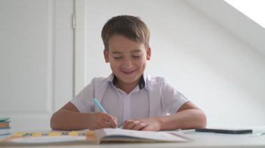 Küçük okul çocuğu ödev yapıyor, kalemle deftere yazıyor.