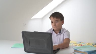 Bilgisayarlı küçük okul çocuğu, internetten uzaktan öğreniyor.