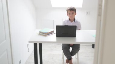 Bilgisayarlı küçük okul çocuğu, internetten uzaktan öğreniyor.