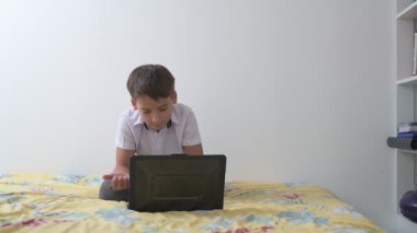 Bilgisayarlı küçük okul çocuğu, internetten uzaktan öğreniyor.