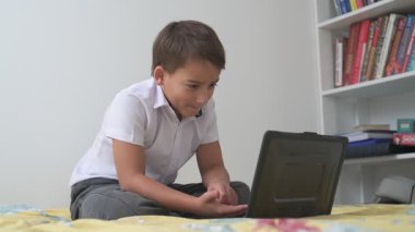 Bilgisayarlı küçük okul çocuğu, internetten uzaktan öğreniyor.