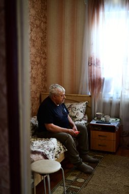 Kanepede oturmuş televizyon izleyen üzgün bir Sovyet ihtiyarın portresi.