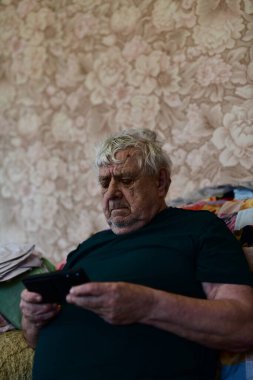 Evde cep telefonu olan yaşlı bir adam.