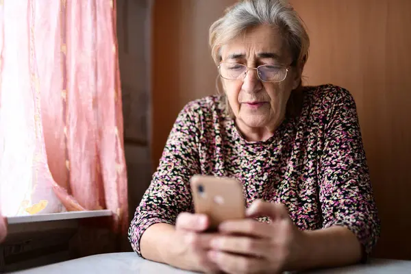 Evde cep telefonu olan yaşlı bir kadın.