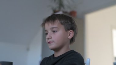 Okul çocuğu okuldan önce mutfakta kahvaltı hazırlıyor, kahve yapıyor ve cep telefonunu kontrol ediyor.