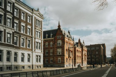 Utrecht, Hollanda - 16 Mart 2024, mavi bulutlu gökyüzü altındaki binalar ve cadde manzarası