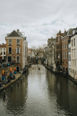 Utrecht, Hollanda - 16 Mart 2024, bulutlu bir günde şehir ve kanal manzarası, kanalda tekne kullanan insanlar