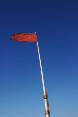 Mavi gökyüzünde kırmızı uyarı bayrağı dalgalanıyor