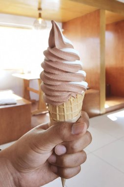 close up of chocolate flavor ice cream in crispy cone on hand