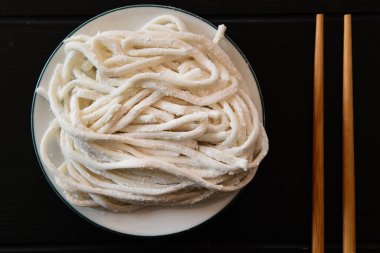 Beyaz tabakta taze udon eriştelerini yakın. 