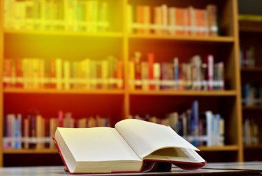 Open Book on wood table and blurred bookshelf in the library, education background, back to school concept at Thailand.