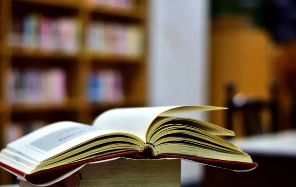 Open Book on wood table and blurred bookshelf in the library, education background, back to school concept at Thailand.