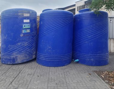 BANGKOK, THAILAND - 25 Haziran 2024: Büyük mavi plastik su tankları, 3000 litre, Tayland kaldırımında yer almaktadır.