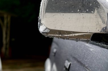 Yağmur damlaları Tayland 'daki otoparkta arabanın yan aynasına düşer..