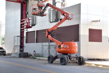 BANGKOK, THAILAND - 17 Kasım 2024: Modern Orange Bucket kamyonu Bangkok, Tayland şantiyesinde bir vinçle yükseliyor.