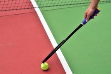 Bir tenis oyuncusu bir elinde tenis topu, diğer elinde tenis raketi tutarken Tayland 'da tenis kortunda tenis oynamaya hazır..